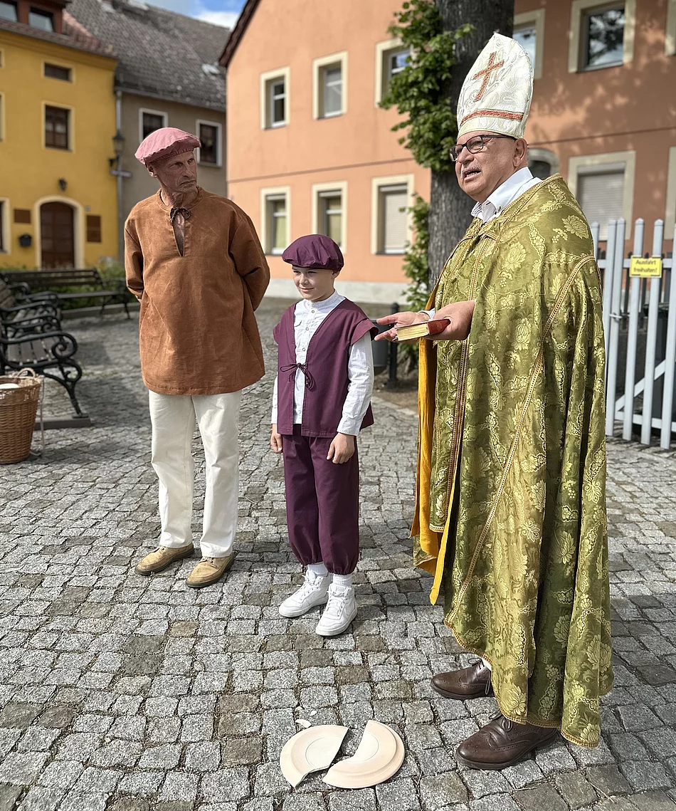 Gottfried Brückner (rechts) führt als Bischof durch die Stadt. Hier begegnet er den Töpfern auf dem Neumarkt, dem früheren „Toppmarkt“. Auch junge Bischofswerdaer beteiligen sich an den „Lebendigen Stadtführungen“, hier Adam Büchler (Mitte) als Töpferjunge. Foto: Stadt Bischofswerda